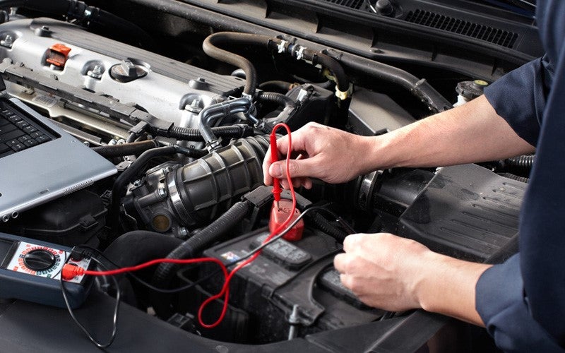 Mechanic using jumper cables under a car hood
